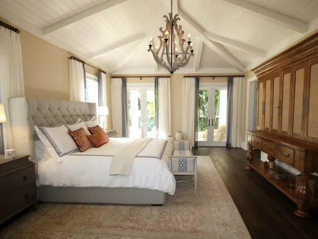 Bright guest bedroom with a freshly made bed, crisp white linens and a chandelier