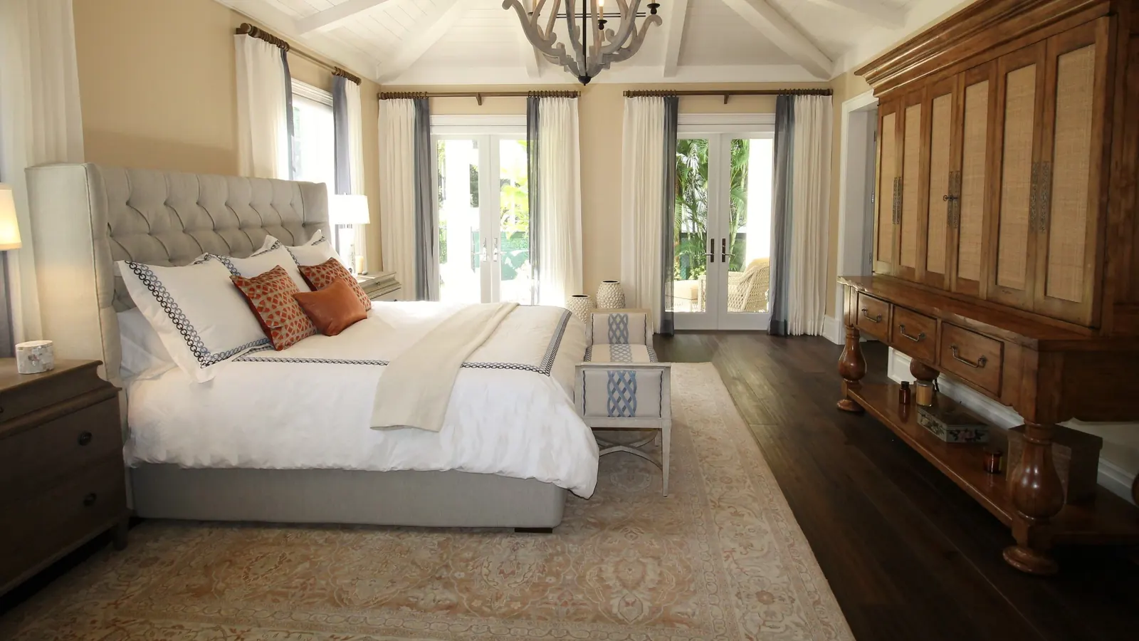 Bright guest bedroom with a freshly made bed, crisp white linens and a chandelier
