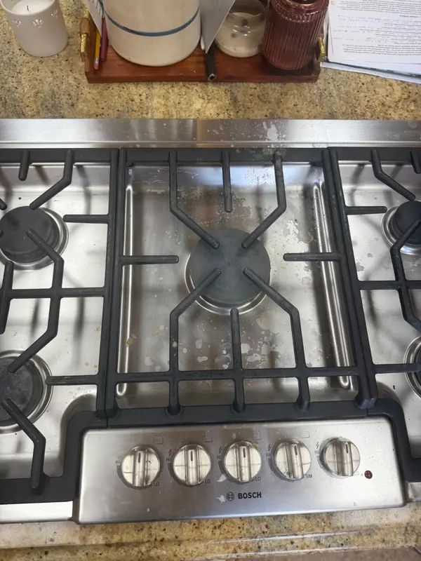 Gas cooktop covered in grease and food residue before cleaning
