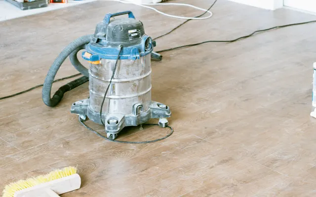 Shop vacuum and broom on the floor of a bright, freshly renovated room
