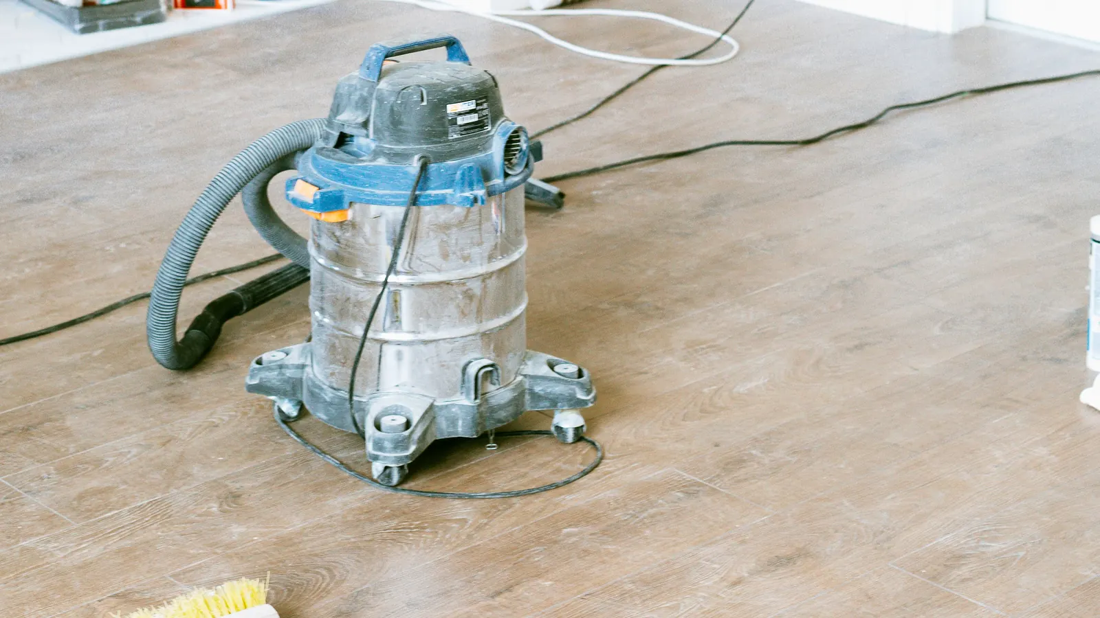 Shop vacuum and broom on the floor of a bright, freshly renovated room