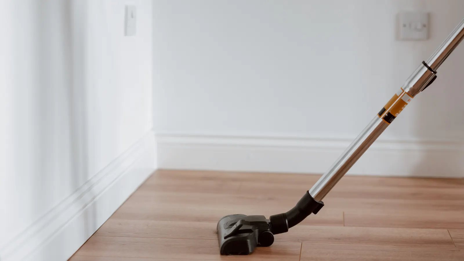 Vacuum cleaning along the baseboard of an empty, freshly vacated room