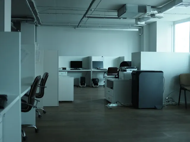 Empty open-plan office with workstations, desk chairs and a printer