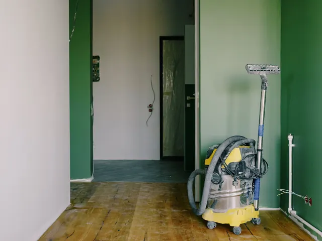Shop vacuum on a dusty wood floor in a freshly renovated room