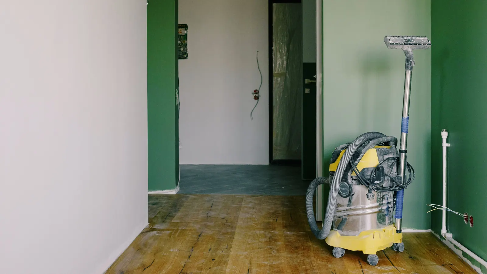 Shop vacuum on a dusty wood floor in a freshly renovated room