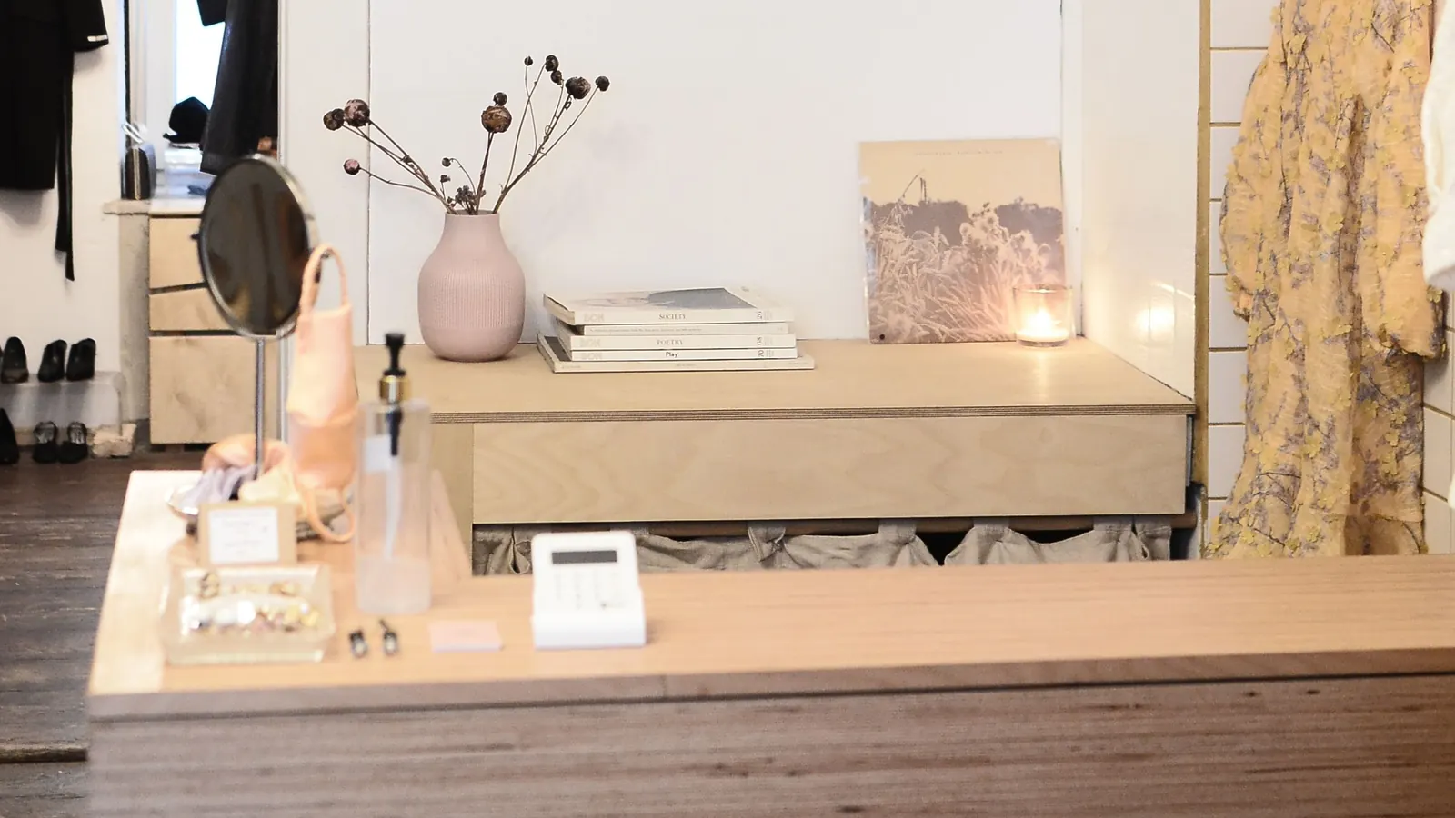 Bright boutique with a wooden sales counter, card reader and clothes on hangers